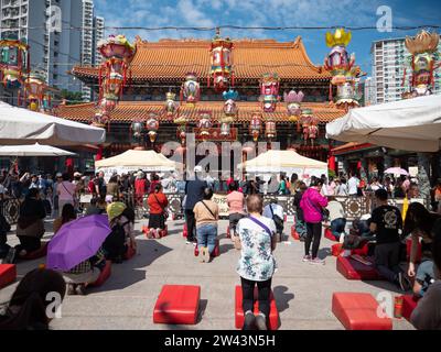 November 2023. Wong Tai Sin Tempel - Wong Tai Sin Gegend, Hongkong. Viele Menschen beten auf den Knien vor dem Haupttempelgebäude Stockfoto