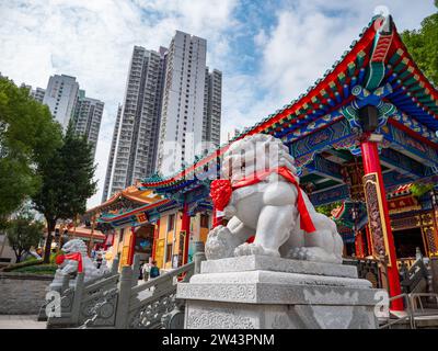 November 2023. Wong Tai Sin Tempel - Wong Tai Sin Gegend, Hongkong. Steinfarbene Statue eines Löwenhundes vor dem Tempelgebäude Wong Tai Sin Stockfoto