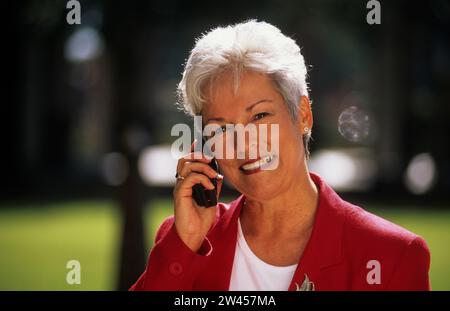 Geschäftsfrau telefoniert im Park mit dem Handy Stockfoto