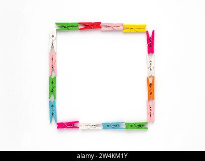 Viele hölzerne mehrfarbige Kleiderschalen liegen in Form eines Quadrats auf weißem Hintergrund. Draufsicht. Leerzeichen für Text. Stockfoto
