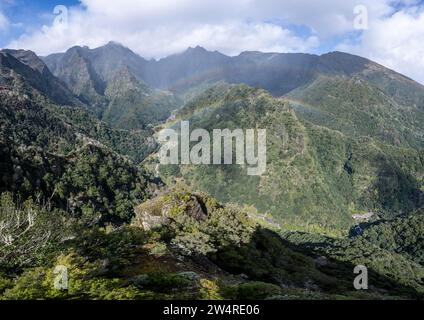 Dicht bewachsene steile Berge mit Regenbogen, grüne Berglandschaft, Blick von Miradouro dos Balcoes, Bergtal Ribeira da Metade und die Stockfoto