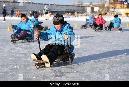 (231221) -- URUMQI, 21. Dezember 2023 (Xinhua) -- Schüler erleben einen Eisschlitten an der Shuixigou-Mittelschule in Urumqi County, nordwestchinesische Autonome Region Xinjiang Uygur, 20. Dezember 2023. Die Shuixigou Middle School, eine neunjährige Bildungsschule im Bezirk Urumqi in Xinjiang, entwickelt ihre Wintersportausbildung seit mehr als 20 Jahren. Die Schüler erhalten elementare Eislaufkurse in den unteren Klassen, danach können sie je nach individuellen Umständen im Eislaufteam, Eishockeyteam oder Eiskunstlauf-Team teilnehmen. Jahre Ausbildung zum Winter-spo Stockfoto