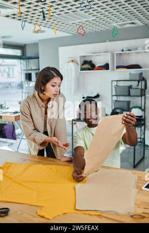 Junge interrassische Modedesigner arbeiten mit Nähmustern im Druckstudio, Kreativität Stockfoto