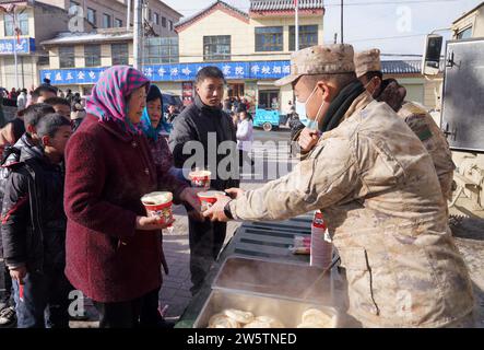 Linxia, Chinas Provinz Gansu. Dezember 2023. Soldaten liefern warme Nahrung für die von Erdbeben betroffenen Menschen in der Gemeinde Liuji, Jishishan County, nordwestchinesische Provinz Gansu, 21. Dezember 2023. Die chinesische Volksbefreiungsarmee (PLA) und die Volksarmee (PAPF) haben mehrere Rettungskräfte in Gebieten eingesetzt, die von Erdbeben betroffen sind, als Reaktion auf ein Erdbeben der Stärke 6,2, das die nordwestchinesische Provinz Gansu am späten Montag erschütterte. Quelle: Zhang Yongjin/Xinhua/Alamy Live News Stockfoto