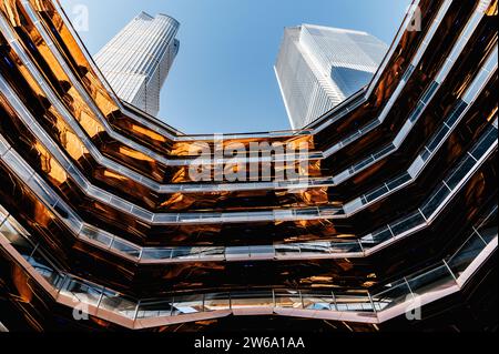 Von unten ist die moderne Struktur von miteinander verbundenen spiralförmigen und miteinander verbundenen beleuchteten Treppen in Hudson Yards in Manhattan, New York gegen Wolken Stockfoto