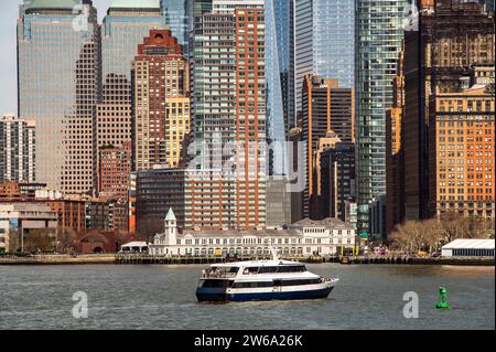 Eine Nahaufnahme der architektonischen Vielfalt Manhattans mit einer Mischung aus alten Backsteinstrukturen und modernen Glashochhäusern. In der Hu wird eine Fähre gesehen Stockfoto