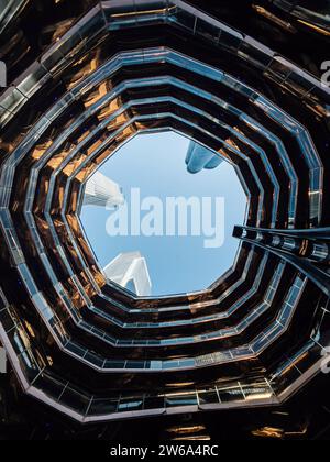 Von unten ist die moderne Struktur von miteinander verbundenen spiralförmigen und miteinander verbundenen beleuchteten Treppen in Hudson Yards in Manhattan, New York gegen Wolken Stockfoto