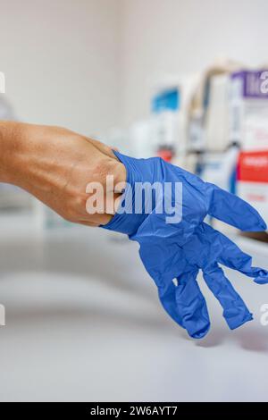 Quergesichtsloser mit blauen Handschuhen in der Hand vor verschwommenem Hintergrund des Krankenhauskorridors Stockfoto
