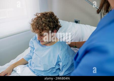 Von oben über der Ernte weibliche Ärztin überprüft Patienten sitzend auf Bett im Krankenhaus während der Arbeit in der Klinik Stockfoto