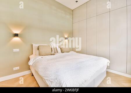 Inneneinrichtung eines luxuriösen, eleganten Schlafzimmers mit gemütlichem weißem Bett und beleuchteten Lampen an der Wand in einem modernen Apartment Stockfoto