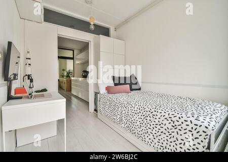 Ein ordentlich organisiertes Studio-Apartment mit einem komfortablen Bett mit stilvoller Bettwäsche, einem eleganten Arbeitsplatz und modernem, urbanem Dekor. Stockfoto