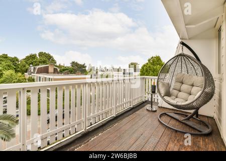 Leere Schaukel auf Balkondiele mit Blick auf die Bungalows und Villen in der Nachbarschaft vor dem Himmel Stockfoto