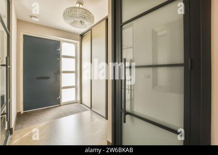 Stilvolles Interieur eines Hauses mit einer modernen Tür mit Glaselementen und einer schicken Deckenleuchte. Stockfoto