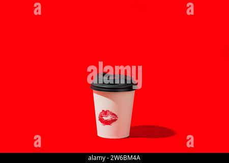 Eine Kaffeetasse aus Papier mit schwarzem Deckel und Lippenstiftmarkierung steht vor einem leuchtend roten Hintergrund und hebt einen kräftigen Kontrast hervor. Stockfoto