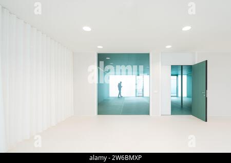 Seitenansicht eines anonymen Mannes durch Glaswand im leeren weißen Raum im Krankenhaus gesehen Stockfoto