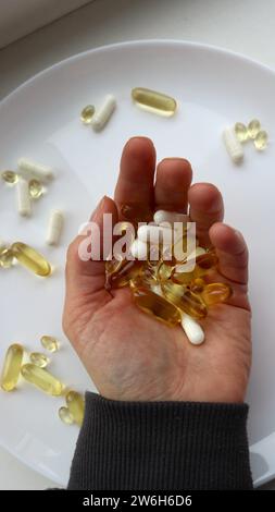 Weibliche Hand mit einer Handvoll Vitamine und Tabletten auf der Handfläche, vertikales Bild, Vitamine in großen Dosen einnehmen Stockfoto