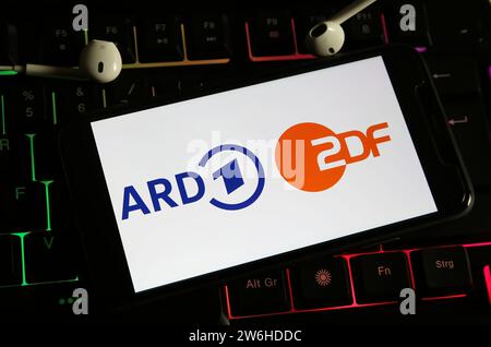 Viersen, Deutschland - 9. Dezember. 2023: Nahaufnahme des Smartphones auf Computertastatur mit Logobeschriftung der öffentlich-rechtlichen Fernsehsender ARD und ZDF Stockfoto