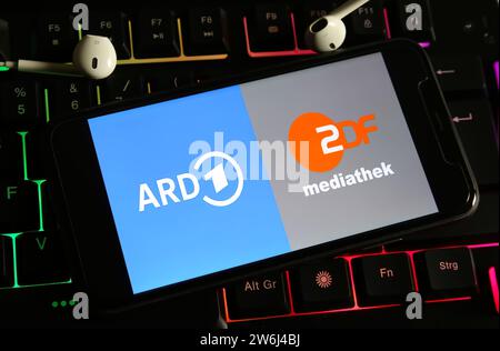 Viersen, Deutschland - 9. Dezember. 2023: Nahaufnahme des Smartphones auf Computertastatur mit Logobeschriftung der öffentlich-rechtlichen Fernsehsender ARD und ZDF Stockfoto