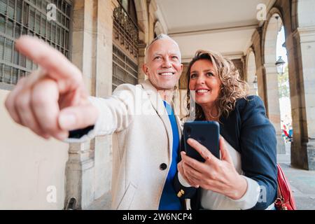 Ein reifes Paar mittleren Alters, das auf einer romantischen Reise mit einer gps-App über ein Mobiltelefon den Standort beobachtet. Verheiratete Leute, die gemeinsam Sehenswürdigkeiten besichtigen und Orte auf dem Smartphone beobachten. Hochwertige Fotos Stockfoto