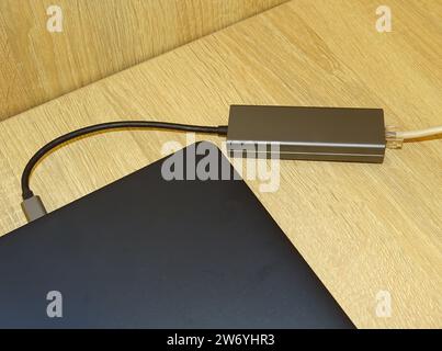 Internet-Kabel, das an eine multifunktionale USB-C-Hub-Station, Ethernet, angeschlossen ist und an einen Laptop angeschlossen ist Stockfoto