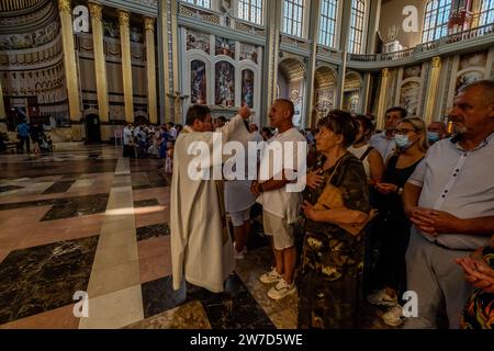 15.08.2021, Polen, Flechten Stary, Wielkopolska - Priester bricht Brot während der Messe über die Himmelfahrt Mariens in der Basilika unserer Lieben Frau von Flechten Stockfoto