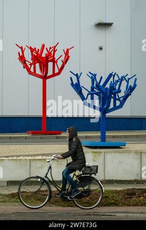 07.11.2023, Deutschland, Bremen, Bremen - Radfahrer vor zwei verlassenen Plastikbäumen am Eingang einer Autowaschanlage. 00A231107D040CAROEX.JPG [MODELL REL Stockfoto