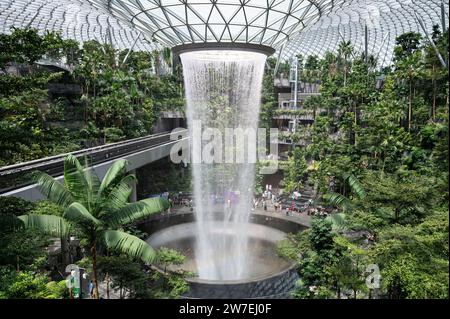 31.07.2023, Singapur, Singapur, - der Garten des Shiseido Forest Valley mit dem Indoor-Wasserfall Rain Vortex im Zentrum des modernen Jewel Termi Stockfoto