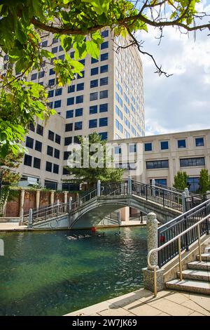 Modernes Gebäude und Fußgängerbrücke über den Kanal in Urban Oasis Stockfoto