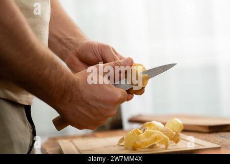 Küchenroutine: Kartoffelhaut mit einem scharfen Peeler entfernen. Stockfoto