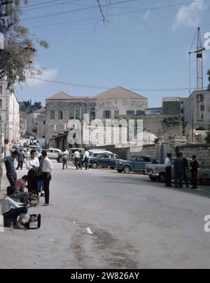 (Originalunterschrift) Nazareth. Straße mit geparkten Autos. Im Vordergrund ein Schuhputzjunge bei der Arbeit ca. Undatiert Stockfoto