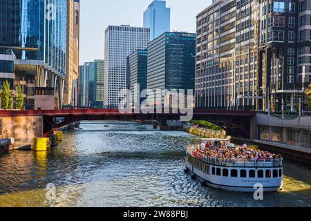 Touristen auf weißem Boot auf dem Chicago Kanal an sonnigen Sommertagen mit Wolkenkratzern auf beiden Seiten Stockfoto