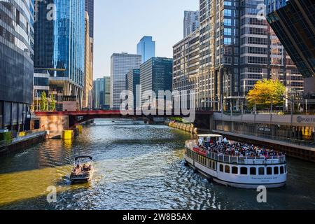 Touristen auf weißem Boot neben kleinerem Schiff auf dem Chicago Canal Waterway mit Wolkenkratzern, Sommertag Stockfoto