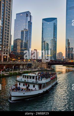 Bootstour mit Touristen auf dem Chicago Kanal mit reflektierendem Sonnenlicht auf Wolkenkratzern, IL, USA Tourismus Stockfoto