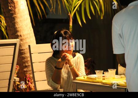 Malediven - 22. September 2013 : in einem Restaurant im Freien serviert ein Kellner bei einer jungen asiatischen Frau in tropischer Atmosphäre abends Essen Stockfoto