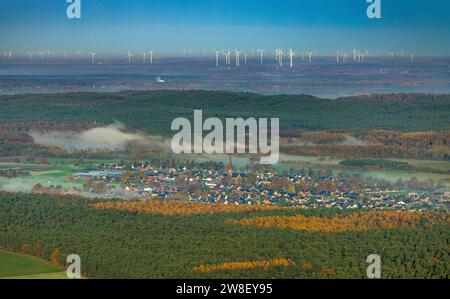 Aus der Vogelperspektive, Nebel über dem Dorf Hullern mit St. Andreas-Kirche, Windturbinenpark im Hintergrund, umgeben von herbstlichen Laubbäumen, Hu Stockfoto