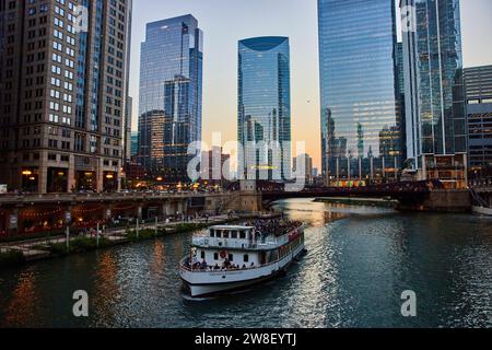 Touristen auf dem Boot entlang des Chicago Canal bei Sonnenaufgang mit blauer Stunde Beleuchtung auf Wolkenkratzern, IL, USA Stockfoto