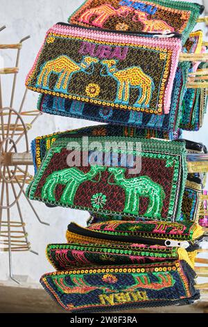 Gestapelte, gestickte Handtaschen mit Kamelmuster, touristische Souvenirs im historischen Viertel Al Fahidi, Dubai, Vereinigte Arabische Emirate Stockfoto
