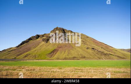 Berg mit Hängen mit grünem Gras in landschaftlich reizvoller Landschaft, Island Stockfoto