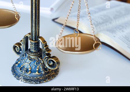 Alte Waage auf weiß mit heiligem Bibelbuch im Hintergrund. Nahaufnahme. Begriff von Gerechtigkeit, Gerechtigkeit, Autorität, christlichem Recht, Ehrlichkeit. Stockfoto