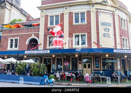 Giant Father Christmas vor dem historischen Harbour View Hotel in Millers Point Sydney, Dezember 2023, NSW, Australien, mit Leuten, die essen und trinken Stockfoto