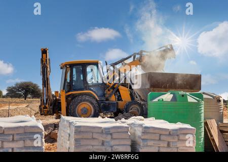 Baggerlader, auf der Baustelle, Laden eines Lastwagens, Zement vorne, afrikanische Entwicklungen Stockfoto