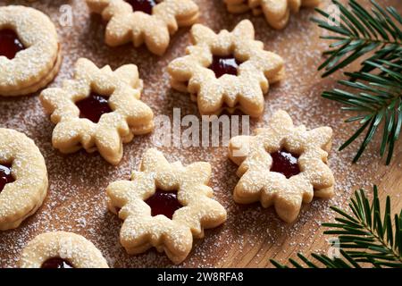 Sternförmige Linzer Weihnachtskekse gefüllt mit Erdbeermarmelade und mit Zucker auf einem Holzbrett bestäubt Stockfoto