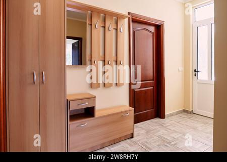 Großer Schrank mit Kleiderbügeln und Spiegel im Flur bei der Tür Stockfoto