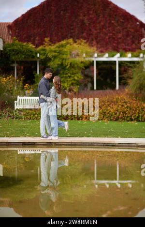 Ein junges Paar küsst und freut sich am See. Schönes junges Paar, das sich im Herbst draußen küsst. Liebevolles Paar, das in der Natur spaziert. Herbststimmung. Glücklicher Mann Stockfoto