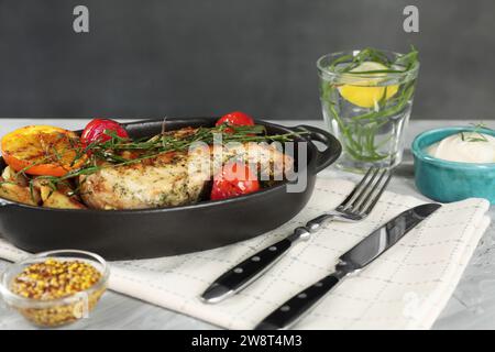 Leckeres Huhn, Gemüse, Getränk mit Estragon und Salatdressings auf grauem Tisch Stockfoto