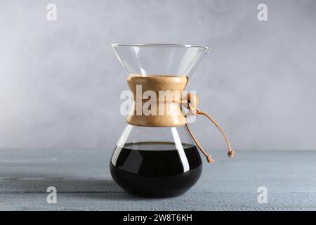 chemex-Glaskaffeemaschine mit leckerem Tropfkaffee auf grauem Holztisch Stockfoto