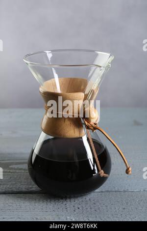 chemex-Glaskaffeemaschine mit leckerem Tropfkaffee auf grauem Holztisch Stockfoto