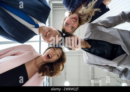 Eine vielfältige Gruppe von Geschäftsleuten steht in einem Kreis inmitten eines Unternehmens zusammen. Stockfoto