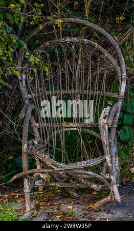 Ein alter verlassener Korbstuhl, alt, im Laufe der Zeit aufgelöst, alt. Einsamkeit, Verlassenheit, alte Zeiten in einem Garten im Herbst Stockfoto