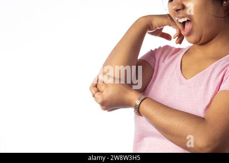 Eine Indianerin, die ihren Ellenbogen wegen Schmerzen hält und einen schmerzhaften Ausdruck auf weißem Hintergrund zeigt Stockfoto